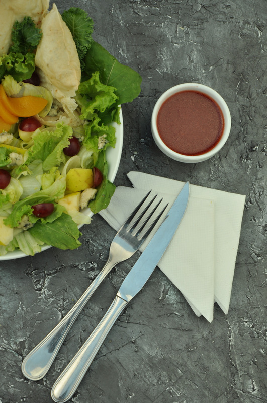 Zeleninovy salat na taliri, zalivka vedle, pribor